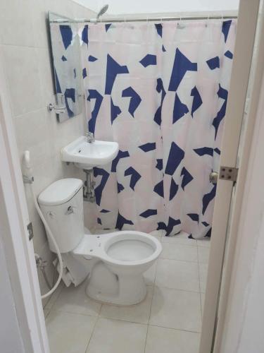 a bathroom with a toilet and a shower curtain at Mamita Seaside Resort in Guinisiliban