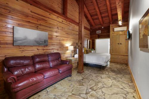 a living room with a leather couch and a bed at Wimberley Log Cabins Resort and Suites- Unit 2 in Wimberley