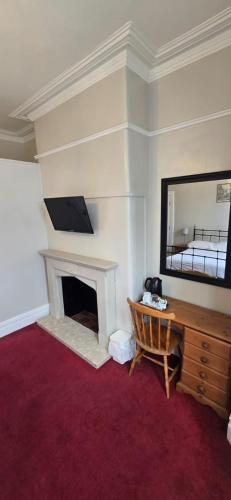 a room with a desk with a mirror and a fireplace at Norfolk Guest House in Bristol