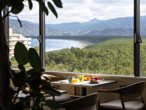 a table and chairs in front of a large window at Mercure Saga Karatsu Resort in Karatsu