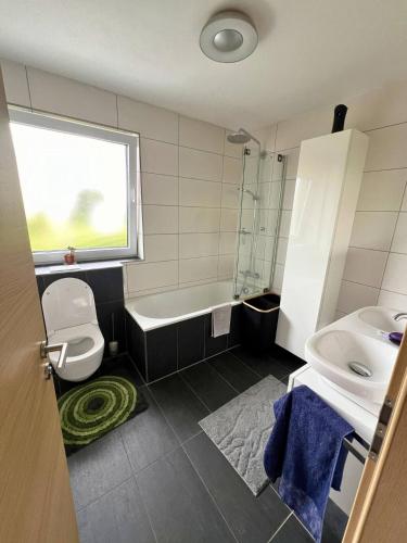 a bathroom with a tub and a sink and a toilet at Modernes Reihenhaus mit Terrasse drei Schlafzimmer fuer sechs Personen in Kempten