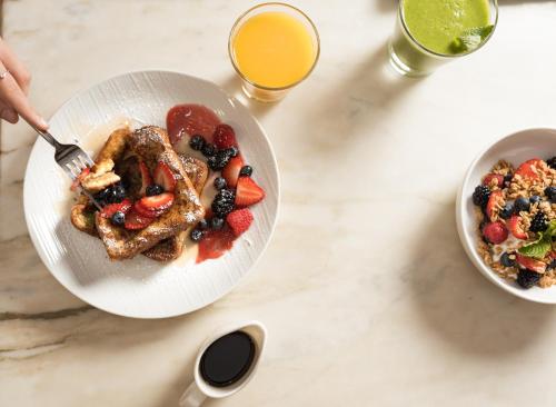 a table with a plate of breakfast food and a bowl of fruit at Montrose at Beverly Hills in Los Angeles