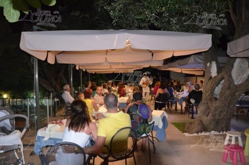 a group of people sitting at tables under an umbrella at Hotel Calanca in Marina di Camerota