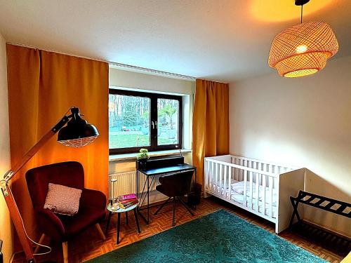 a nursery with a crib and a chair and a window at Familienfreundliche Ferienwohnung mit Garten & Spielplatz nahe Nürnberg Playmobil FunPark in Veitsbronn