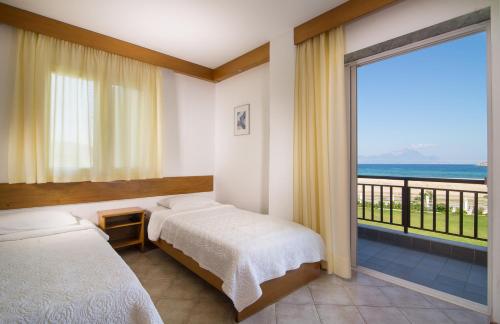 a bedroom with two beds and a view of the ocean at Linaraki Studios & Apartments in Sykia Chalkidikis