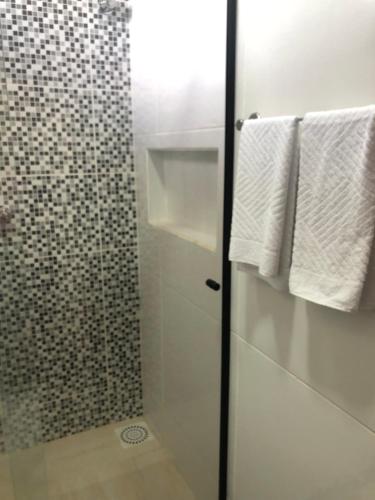 a bathroom with a glass shower door with towels at Pousada casa sonho do mar in Fortim