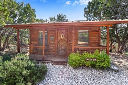 a cabin with a wooden deck in the woods at Cozy Cabin in Wimberley