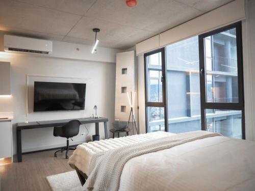 a bedroom with a bed and a desk and a television at Secrt Escalante Premium Studio AC in San Pedro