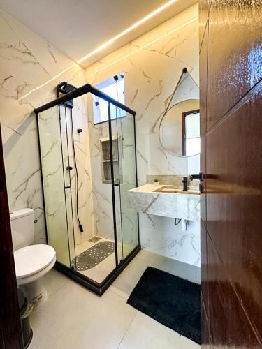a bathroom with a glass shower and a toilet at Casa Condeixa in Cabo Frio