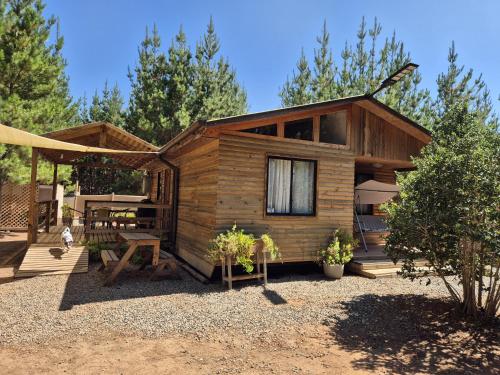 a small wooden cabin with a picnic table and a bench at Cabañas Pinos del Mar in Algarrobo