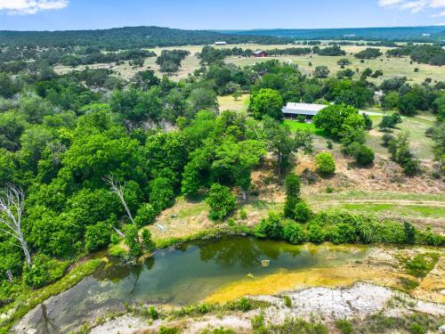 an aerial view of a farm with a pond at River Nest in Wimberley