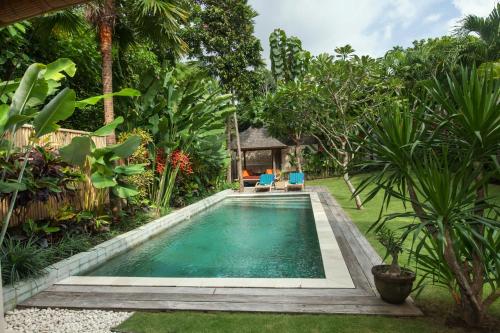 una piscina en medio de un jardín en Villa Liang by Nagisa Bali, en Seminyak