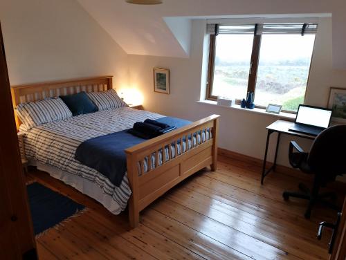 a bedroom with a bed and a desk with a laptop at Ardnacassa in Kilcrohane