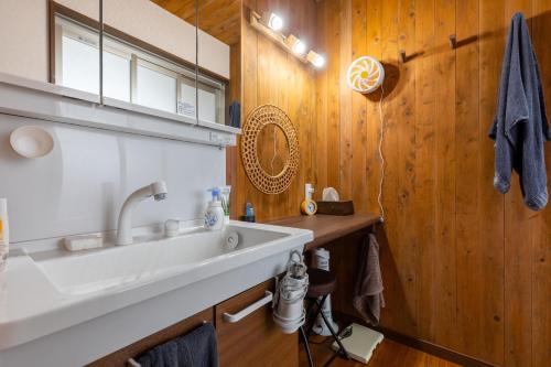 a bathroom with a sink and a wooden wall at まるで映画館 本格シアター 寝室6部屋 大家族大集合 海まで徒歩すぐ ---オーシャニア一宮--- in Ichinomiya