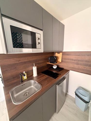 a small kitchen with a sink and a microwave at Le Studio Morny in Deauville