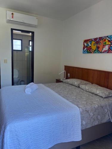 a bedroom with a bed with a white blanket at Cond Residencial Resort Pipa Chalés Triplex - Centro de Pipa in Pipa