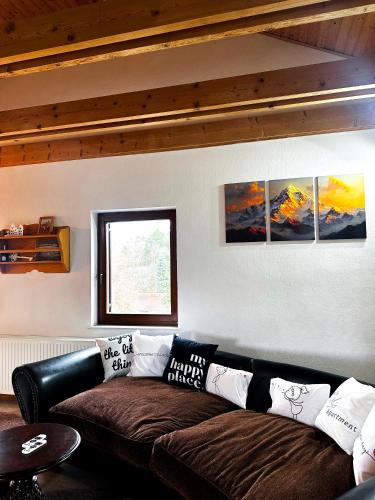 a couch in a living room with four paintings on the wall at Apartment nahe Semmering mit Sauna, Kamin & Terrasse in Enzenreith