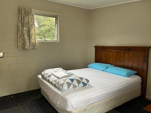 a bedroom with a bed with blue pillows and a window at Fairlie Holiday Park in Fairlie
