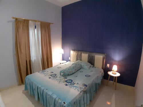 a bedroom with a large bed with a blue wall at Orange Villa in Berastagi