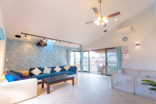 a living room with a blue couch and a ceiling fan at まるで映画館 本格シアター 寝室6部屋 大家族大集合 海まで徒歩すぐ ---オーシャニア一宮--- in Ichinomiya