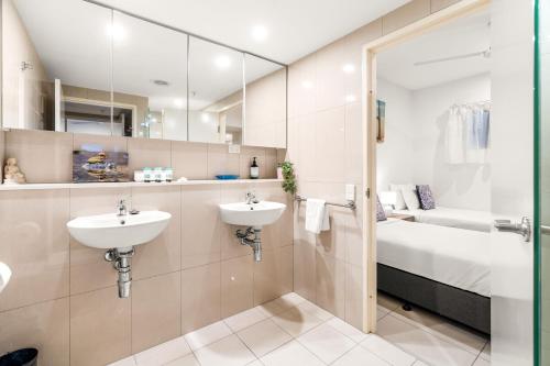 a bathroom with two sinks and a bed and a mirror at Reef-side Splendour City Vistas - Pool - Workspace in Darwin