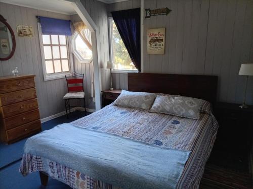 a bedroom with a bed and a dresser and windows at Habitación Bosque Mar in Isla Negra