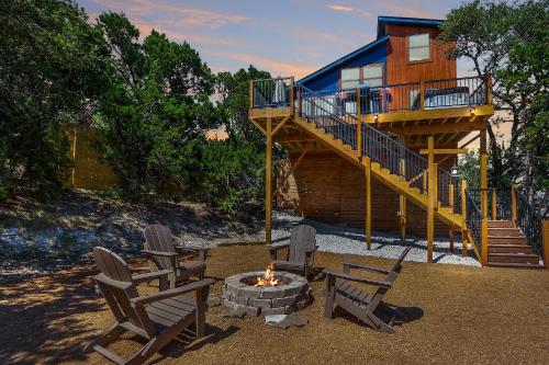 a house with a deck and two chairs and a fire pit at Scenic Treehouse in Canyon Lake