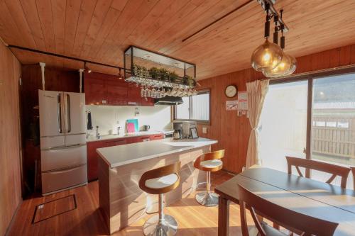 a kitchen with a refrigerator and a table with chairs at まるで映画館 本格シアター 寝室6部屋 大家族大集合 海まで徒歩すぐ ---オーシャニア一宮--- in Ichinomiya