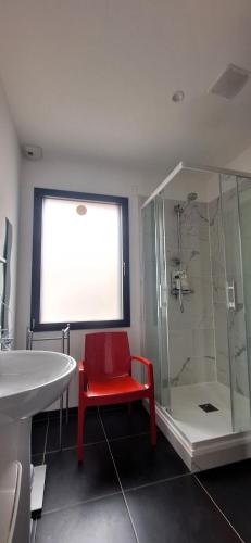 a bathroom with a red chair and a shower at A L'OMBRE DES 2 TILLEULS maison d'hôtes adults only in Sainte-Pazanne
