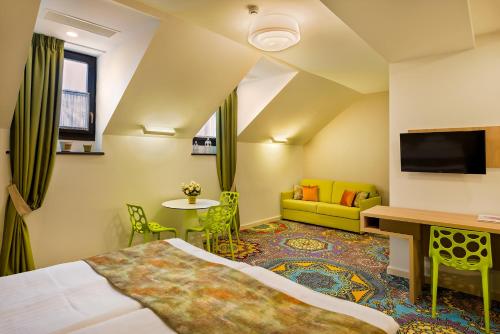 um quarto de hotel com uma cama, uma secretária e um sofá em Blumenhaus Sibiu em Sibiu