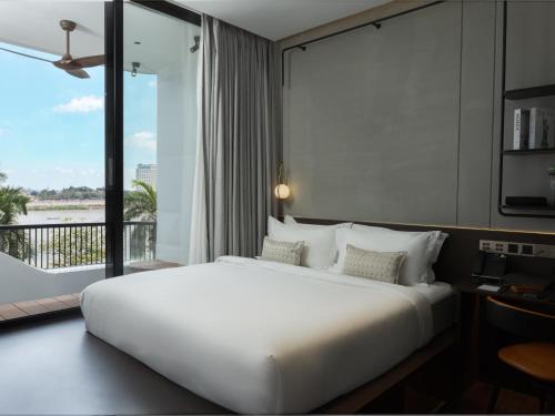 a white bed in a room with a large window at SEENERGY STAY Riverside in Phnom Penh
