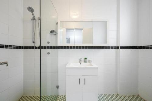 a white bathroom with a sink and a shower at Collaroy 3Br Beach Home with Large Pool Ground Floor in Collaroy