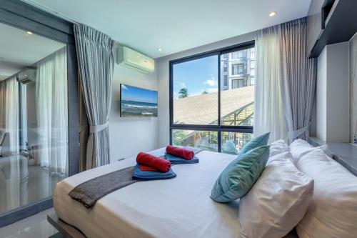 a bedroom with a bed with pillows and a large window at 2BR Family Condo with a Pool View - CTG P205 in Kamala Beach