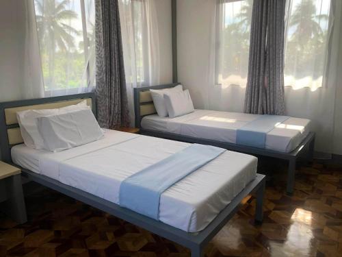two beds sitting in a room with windows at D Estelita Guest House in Moalboal