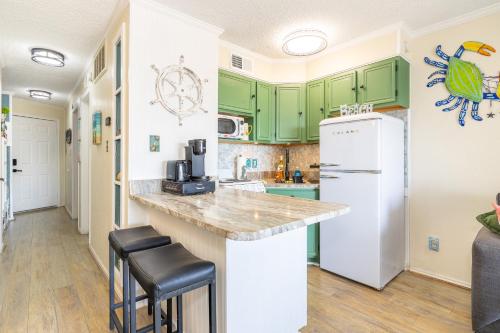 a kitchen with green cabinets and a white refrigerator at Casa Del Mar Unit 257 - Stunning Front Angle Views at the Gulf n Babe's Beach with Private Balcony WiFi in Galveston