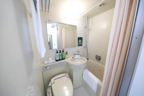 a bathroom with a sink and a toilet and a mirror at Smile Hotel Sugamo in Tokyo
