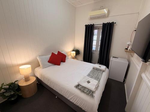 a bedroom with a bed with red pillows and a television at Hotel Metropole Proserpine in Proserpine