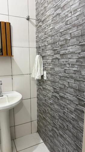 a bathroom with a sink and a brick wall at Suíte aconchegante 2 in Nova Mutum
