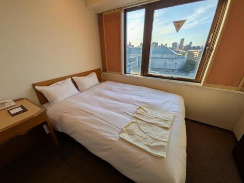 a bedroom with a white bed and a window at Smile Hotel Sugamo in Tokyo