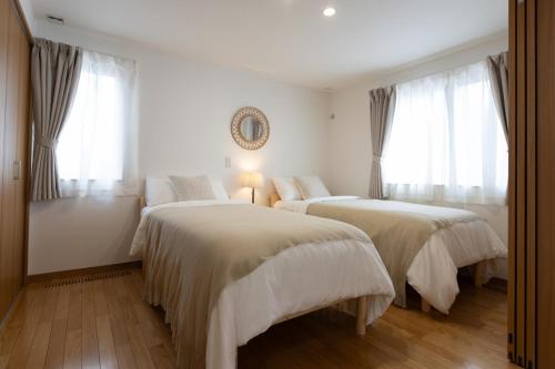 two beds in a white room with windows at Sa one ko Matsumoto Entire house Free parking 2cars in Matsumoto
