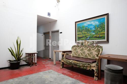 a living room with a chair and a painting on the wall at Griya Aneka Malioboro Yogyakarta Mitra RedDoorz in Yogyakarta