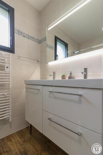 a white bathroom with a sink and a mirror at Les bichous in Saint-Thomas