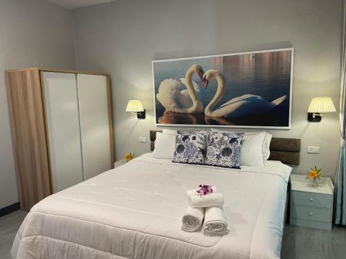 a bedroom with a large white bed with two swans at Butterfly Home Mai Khao Phuket in Ban Suan Maphrao