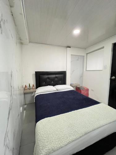 a bedroom with a bed with a blue and white blanket at Apartamento cerca mall plaza in Manizales