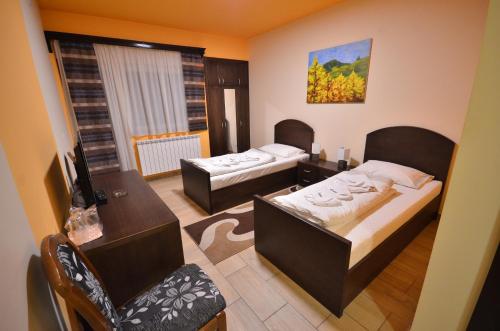 Kleines Zimmer mit 2 Betten, einem Tisch und einem Schreibtisch. in der Unterkunft Hotel Lane in Sjenica