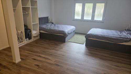 two beds in a room with a wooden floor at Spacious Apartment for 8 Guests in Tuttlingen
