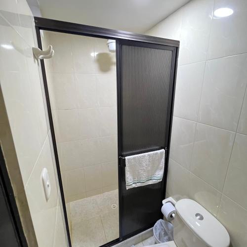 a bathroom with a toilet and a glass shower door at Apartamento cerca mall plaza in Manizales