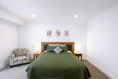 a bedroom with a green bed and a chair at Sky Tower Studio - Pools, Spa, Gym & Super King in Auckland
