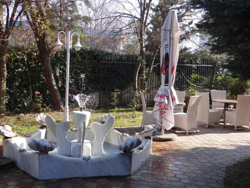 a fountain with an umbrella and chairs and a table at Hotel Konti in Korçë