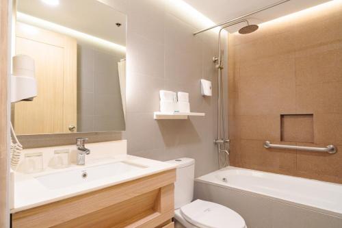 a bathroom with a sink and a toilet and a tub at Microtel by Wyndham Batangas in Santo Tomas